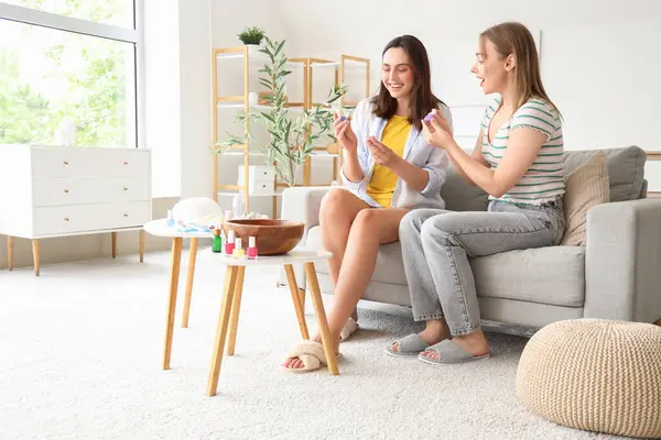 Oturma odasında pedikür için oje seçen genç kadınlar.