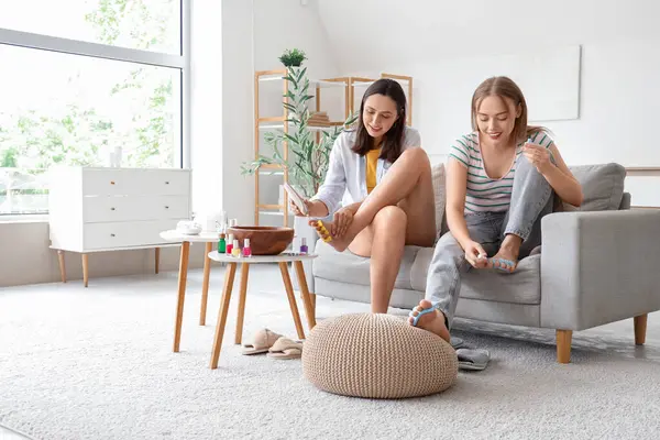 Oturma odasında pedikür yapan genç kadınlar.