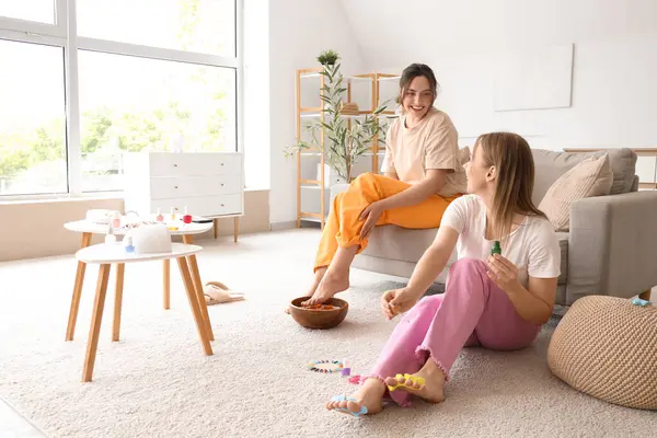 Kozmetik yağlı genç kadınlar oturma odasında pedikür yapıyorlar.