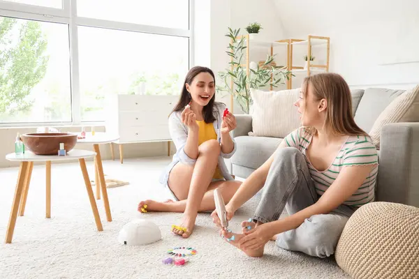 Oturma odasında pedikür yapan genç kadınlar.