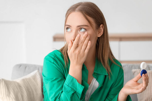 Young woman putting in contact lenses at home