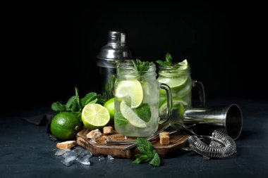 Mason kavanozu soğuk mojito ve koyu arkaplanda malzemeler.