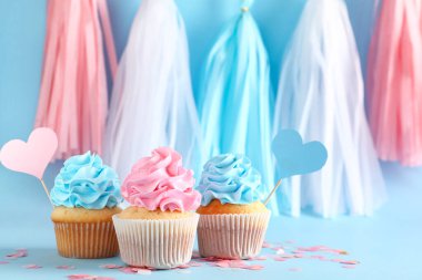 Mavi arka planda süslemeleri olan lezzetli kekler. Cinsiyet ortaya çıkan parti kavramı