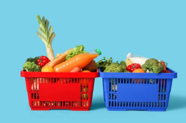 Mavi arka planda yiyecek dolu alışveriş sepetleri