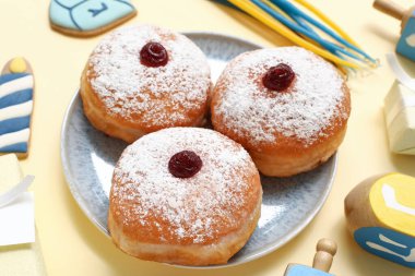 Renkli arkaplanda Hanuka kutlaması için lezzetli çörekler ve dekor tabağı.