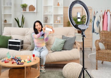 Kadın Asyalı güzellik blogcusu, evinde video kaydediyor.