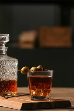 Bir bardak eski moda kokteyl, zeytin ve kaşık ile ahşap masa