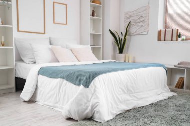 Büyük yataklı, raf üniteli ve çerçeveli aydınlık yatak odasının içi