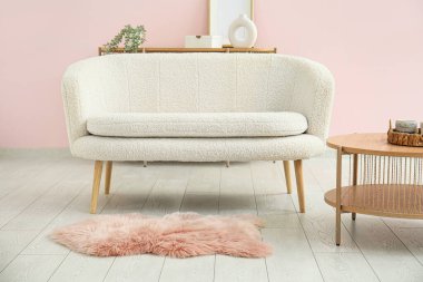 Oturma odasında halı ve kahve masası olan rahat beyaz bir kanepe.