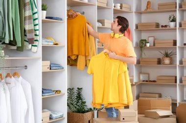 Soyunma odasında şık kıyafetler ayarlayan yakışıklı genç adam.