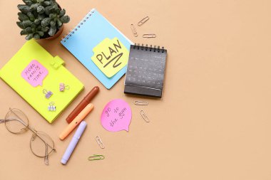Üzerinde planlar, yapışkan notlar ve bej arka plan takvimi olan bir defter. Yeni yıl hedefleri kavramı