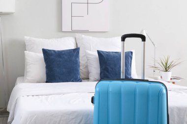 Hafif otel odasında, yatağın yanında bavul, yakın plan.