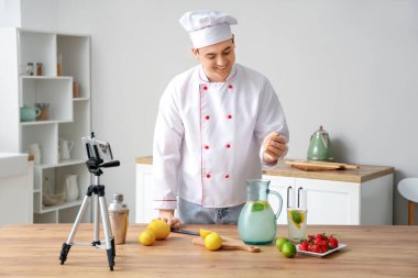 Erkek şef onun mutfakta ev yapımı limonata yaparken videosunu kaydediyor.