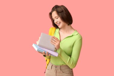 Pembe arka planda kitapları ve sırt çantası olan güzel bir kız öğrenci.