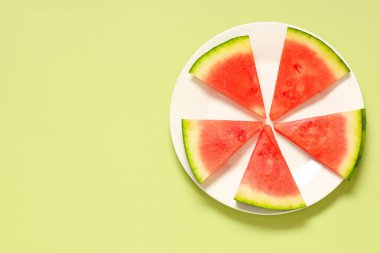 Yeşil zemin üzerinde tatlı karpuz parçaları olan bir tabak.