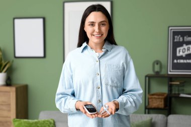 Evde mavi farkındalık kurdelesi ve glukometresi olan şeker hastası genç bir kadın var.