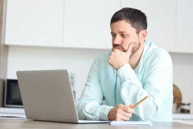 Evde online ders veren kafası karışmış bir erkek öğretmen.