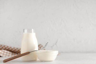 Beyaz arka planda cam kase ve bir şişe lezzetli yoğurt.