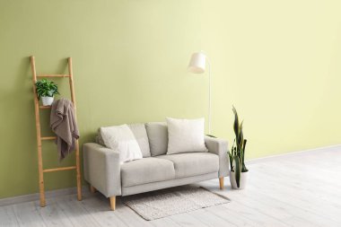 Gri kanepe, lamba ve merdivenli oturma odasının içi.