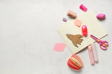 İşaretli kağıt roket ve beyaz arka planda farklı kırtasiye malzemeleri. Üst görünüm