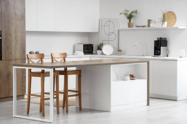 Modern ada masası ve beyaz tezgahlı aydınlık mutfak.