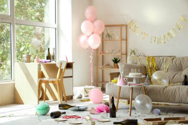 Doğum gününden sonra kanepe, masa ve parti dekoruyla dağınık oturma odasının içinde.