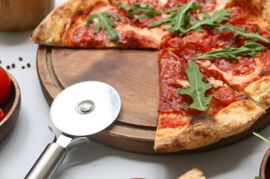 Hafif arka planda lezzetli pizza ve kesiciler, yakın plan.