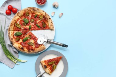 Lezzetli pizzalı kompozisyon, malzemeler ve mavi arka planda kesici.