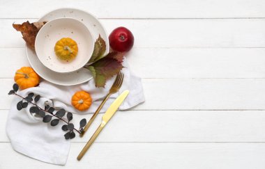 Beyaz ahşap arka planda balkabakları ve sonbahar yapraklarıyla güzel bir masa.