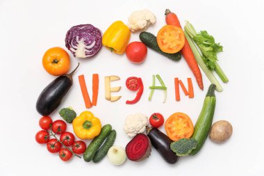 VEGAN sözcüğüyle kompozisyon ve arka planda farklı taze sebzeler