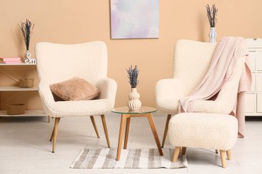 Rahat koltukları ve lavanta çiçekleri olan modern oturma odasının şık bir iç mekanı.