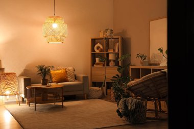 Geceleri oturma odasının içinde rahat bir kanepe, koltuk ve kahve masası.