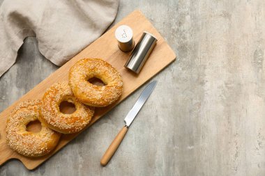 Gri arka planda susam tohumları olan lezzetli simit tahtaları.