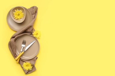 Sarı arka planda güzel kasımpatı çiçekleri olan şık bir masa.