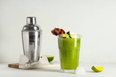 Mermer kesim tahtası, beyaz arka planda pastırma, limon ve kerevizle süslenmiş bir bardak Bloody Mary kokteyli.