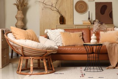 Oturma odasının içinde deri kanepe, hasır koltuk ve sehpa var.