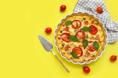 Sarı arka planda ıspanak yapraklı lezzetli domates tartı.