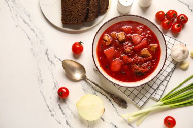 Ekmek dilimleri ve beyaz arka planda malzemelerle bir kase lezzetli Ukrayna çorbası.
