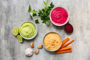 Maydanozlu, pancar ve havuçlu ve grunge arkaplanlı farklı lezzetli humuslar.