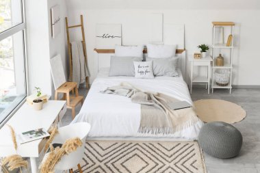 Konforlu yatak odası, puf ve pencerenin yanındaki çalışma alanı