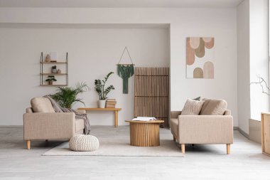 Rahat gri koltukları, kahve masası ve çiçekleri olan şık bir oturma odası.