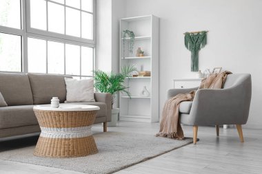 Oturma odasının içinde yumuşak kanepe, koltuk ve rattan masa var.