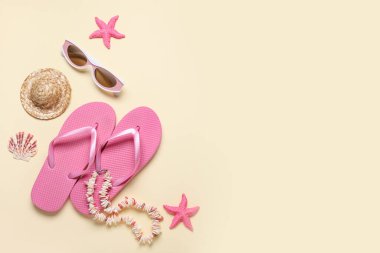 Güneş gözlüğü, kolye, dekoratif şapka ve bej arka planda parmak arası terlik.