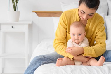 Anne küçük bebeğine yatak odasında masaj yapıyor.