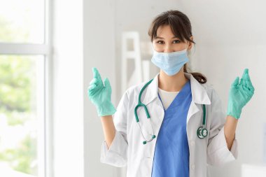 Klinikte maskeli ve eldivenli bir kadın stajyer.