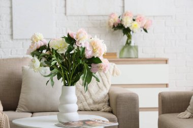 Güzel şakayık demeti ve dergi dolu vazo şık oturma odasındaki sehpanın üstünde, yakın plan.