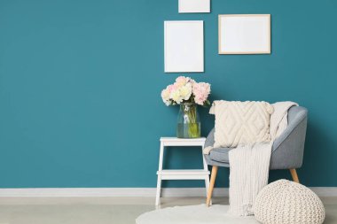 Mavi koltuklu, kahve masalı ve güzel şakayıklı şık bir oturma odası.