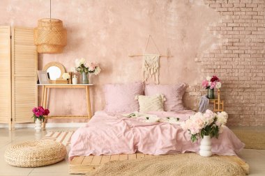 Şık bir yatak odası, rahat bir yatak ve güzel şakayıklar.