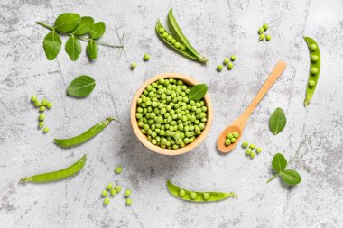 Gri arkaplanda taze bezelye ve kâse ile kompozisyon