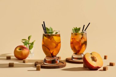 Bej arkaplanda nane ve şeftalili lezzetli buzlu çay.